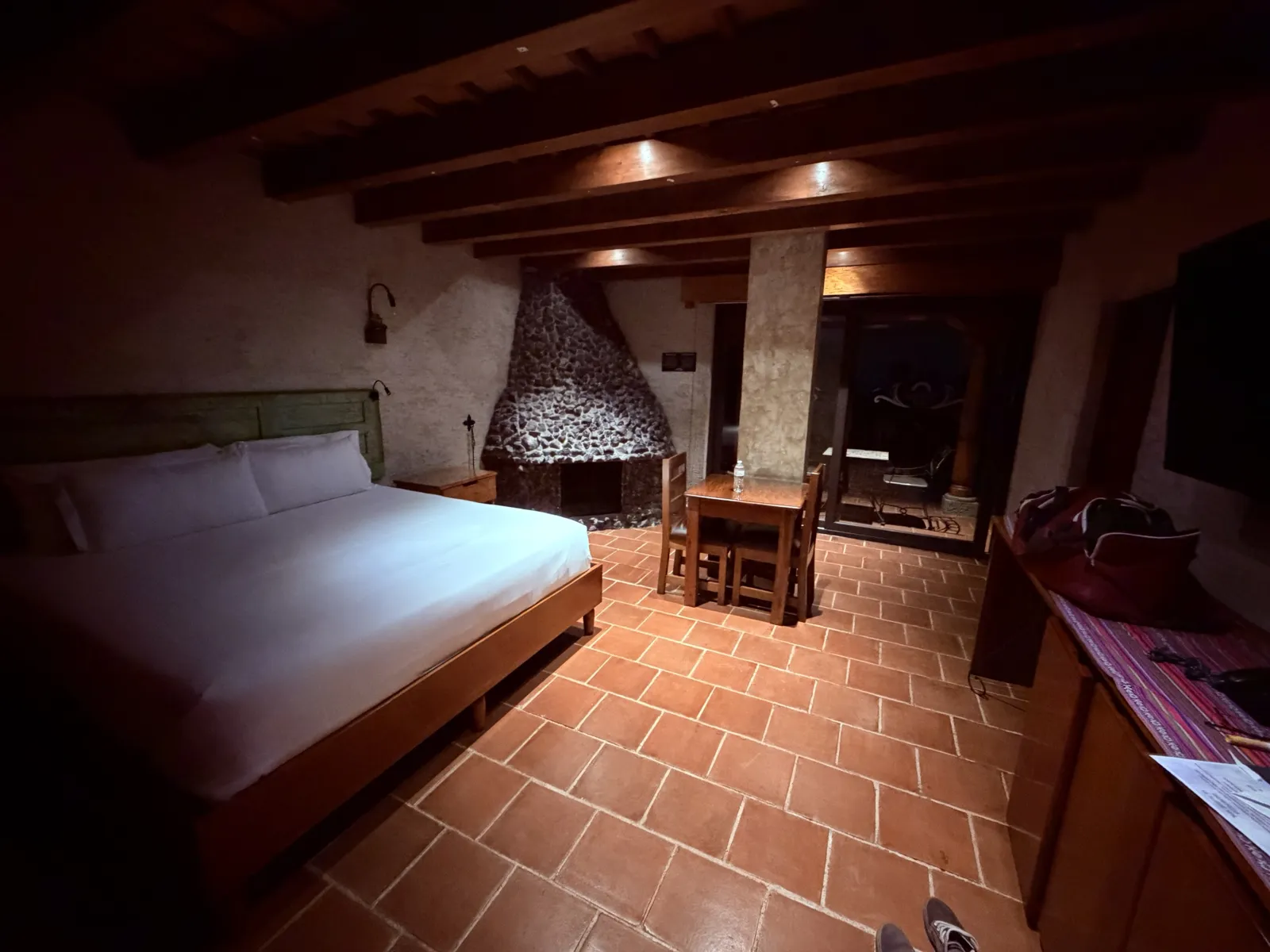 The room: king bed, beamed ceiling, stone fireplace.