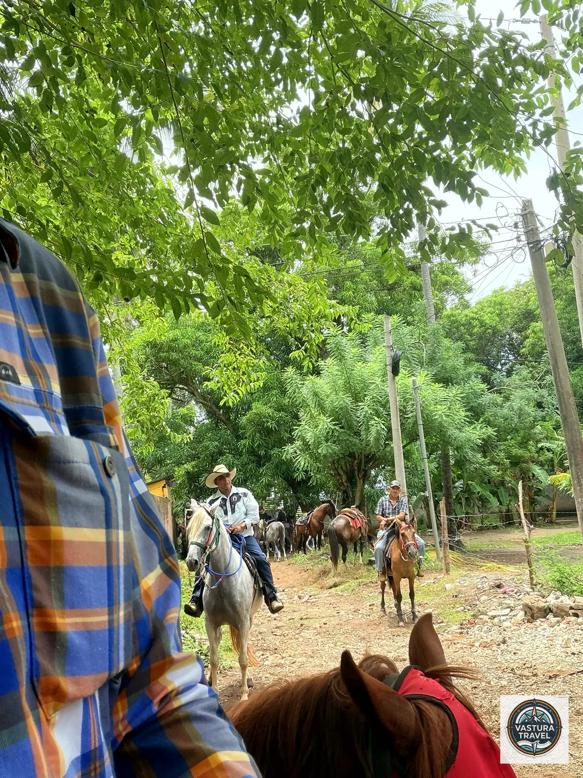 Riders gathering on a dirt lane for the cabalgata, seen over my horse's ears.